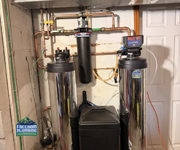 A section of copper plumbing featuring significant limescale buildup and crusting around the threaded connections and valves.