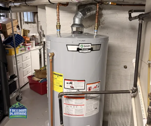 Close-up of a corroded copper pipe joint with heavy white mineral deposits and green oxidation in a dark utility area.